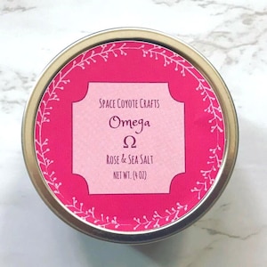 May include: A silver tin with a pink label that says "SPACE COYOTE CRAFTS Omega Ω ROSE & SEA SALT NET WT. (4 OZ)" with a white floral border.