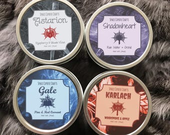 May include: Four round metal tins with colorful designs and labels. Each tin has a different name and scent. The names are Astarion, Shadowheart, Gale, and Karlach. The scents are Raspberry & Black Violet, Rain Water & Orchid, Pine & Red Currant, and Woodsmoke & Apple. Each tin is 4 ounces.