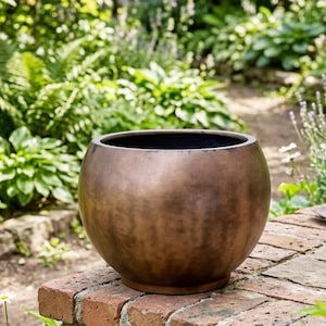 May include: A round, bowl-shaped planter with a smooth, dark bronze-colored metallic finish. The vessel features a wide, open top and a slightly tapered base, showcasing a consistent, weathered patina across its curved exterior surface.
