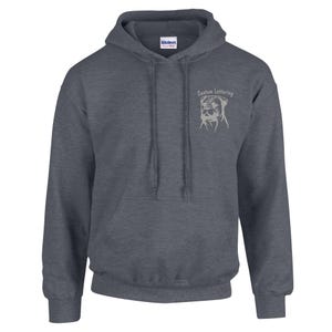 May include: A dark gray hooded sweatshirt with a front pocket and drawstring. The upper right chest features the text "Custom Lettering" above a light-colored graphic of a dog's face. The brand name "GILDAN" is visible on the inside of the hood.