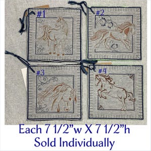May include: Four gray fabric squares, each with a different embroidered horse design in brown thread. Each square is 7.5 inches wide and 7.5 inches high. The squares are trimmed with dark blue stitching and have a dark blue string attached.