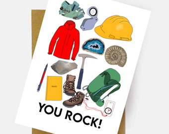 May include: A greeting card with illustrations of geology-related items, including a red jacket, hiking boots, a yellow hard hat, and a backpack. The card reads "YOU ROCK!" in bold black letters.