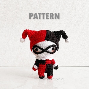 May include: Crochet pattern for a red and black jester doll with a white mask. The pattern is titled "PATTERN".