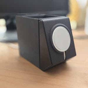 Könnte beinhalten: Ein schwarzer 3D-gedruckter Ständer mit einem runden Ausschnitt für eine Smartwatch. Der Ständer hat ein elegantes, modernes Design.