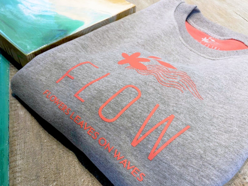 May include: Gray sweatshirt with a coral pink graphic design that says "FLOW" with the words "FLOWERS LEAVES ON WAVES" underneath.