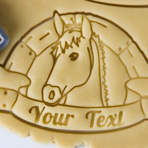 Puede incluir: Un cortador de galletas con forma de cabeza de caballo con una pancarta debajo que dice "Your Text".