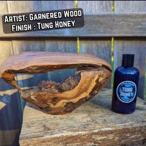 May include: A wooden bowl with a unique shape and a hole in the center. The bowl is finished with Tung Oil, a natural oil that protects and enhances the wood's beauty. The bowl is sitting on a wooden surface next to a bottle of Tung Oil.