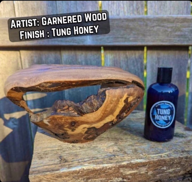 May include: A wooden bowl with a unique shape and a hole in the center. The bowl is finished with Tung Oil, a natural oil that protects and enhances the wood's beauty. The bowl is sitting on a wooden surface next to a bottle of Tung Oil.