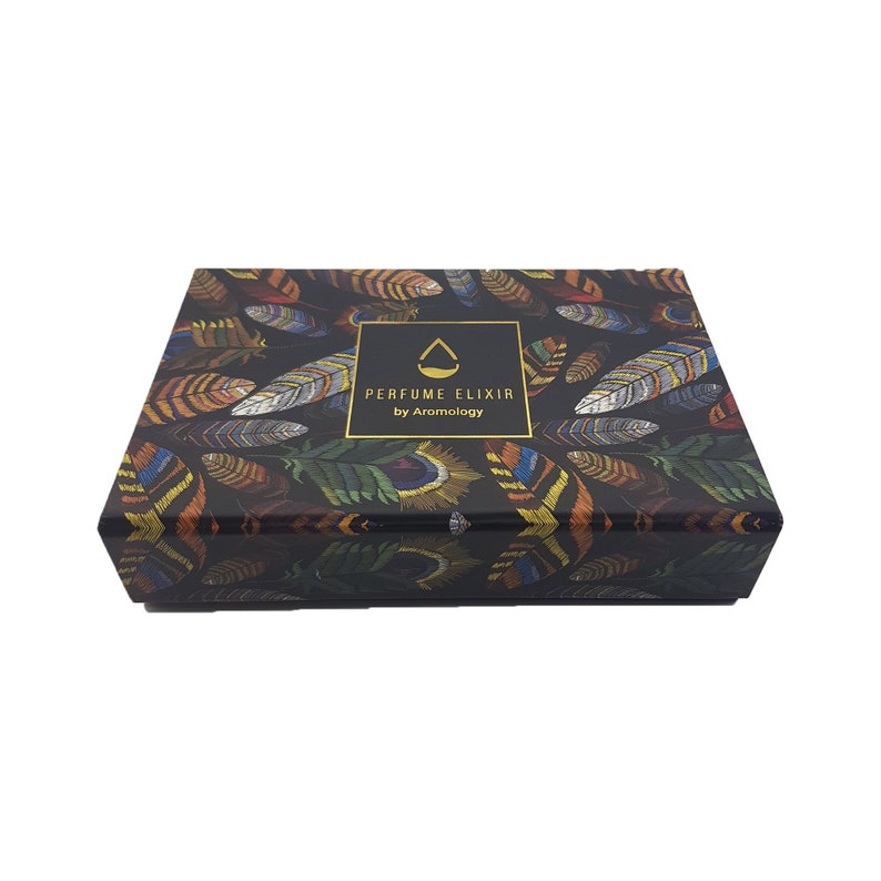 May include: A rectangular box with a black background and a pattern of colorful feathers. The box has a gold-framed label that reads "PERFUME ELIXIR by Aromology". The feathers are in shades of orange, yellow, green, and blue.