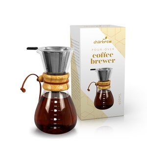 Puede incluir: Una cafetera de vertido de vidrio transparente con un filtro de acero inoxidable, un collar de madera y un asa de cuero. La cafetera tiene una capacidad de 600 ml y está llena de café preparado. La caja junto a ella dice "charbrew POUR-OVER coffee brewer".