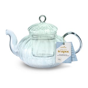 Puede incluir: Tetera de vidrio transparente con boquilla y asa curvadas. La tetera tiene una tapa con un pequeño pomo y un infusor incorporado. Una etiqueta dice "charbrew teapot" y "1000ml glass".