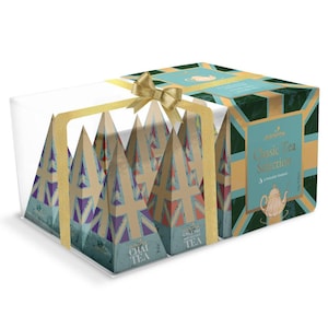 Puede incluir: Una caja de regalo de pirámides de té surtidas en un recipiente de plástico transparente. La caja está decorada con un patrón de Union Jack y las palabras "Classic Tea Selection". La caja está atada con una cinta y un lazo dorados.