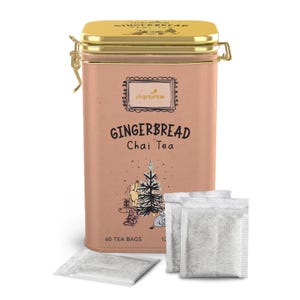 Puede incluir: Una lata rectangular marrón claro con tapa y cierre dorados, etiquetada como "Gingerbread Chai Tea". La lata presenta una ilustración decorativa y el texto "charbrew". Varias bolsitas de té son visibles frente a la lata. La lata contiene 60 bolsitas de té.