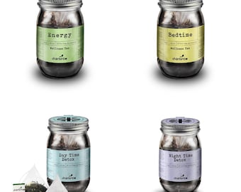 May include: Four glass jars filled with tea bags. The jars are labelled with the text "Energy", "Bedtime", "Day Time Detox", and "Night Time Detox". Each jar has a green, yellow, blue, or purple label with the text "charbrew" on it.