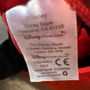 K&ouml;nnte beinhalten: Ein wei&szlig;es Etikett mit dem Disney-Logo und Store-Informationen aus Pasadena, CA, und London, UK. Das Etikett enth&auml;lt auch die Artikelnummer des Verk&auml;ufers und gibt an, dass es aus recyceltem Material hergestellt wurde.