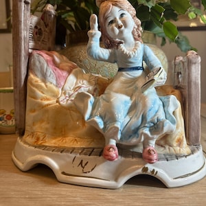 Capodimonte figurine of girl sitting on a bed. Made in Italy