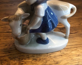 Beautiful French porcelain vintage Dutch milk maid in traditional costume feeding a cow