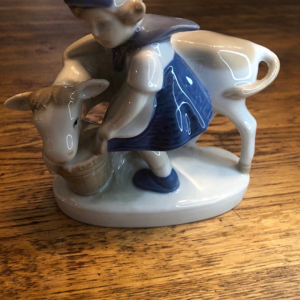 Beautiful French porcelain vintage Dutch milk maid in traditional costume feeding a cow