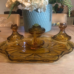 Könnte beinhalten: Ein Satz aus Serviergeschirr aus bernsteinfarbenem Glas mit gewelltem Rand. Das Set enthält eine kleine Schale mit einem Ringhalter, zwei kleine Schalen mit Deckeln und ein großes Serviertablett.