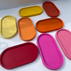 May include: Assortment of ten colorful oval-shaped ceramic trays. The trays are in various shades of red, orange, yellow, and pink.
