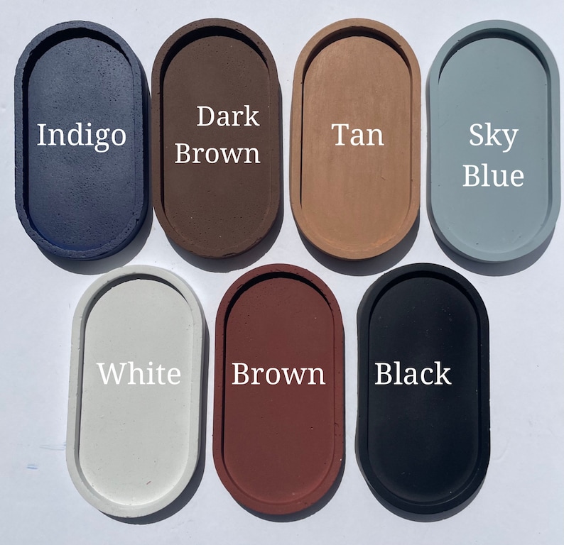 May include: Seven oval-shaped trays arranged in two rows. The top row features colours labelled Indigo, Dark Brown, Tan, and Sky Blue. The bottom row features colours labelled White, Brown, and Black. Each tray has a smooth, solid-coloured surface.