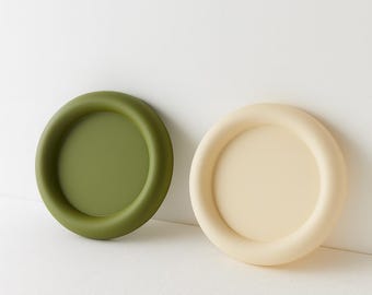 Peut inclure: Deux plateaux ronds, l'un vert olive et l'autre crème. Chacun a un bord arrondi surélevé. Les plateaux sont probablement destinés à un usage décoratif ou fonctionnel. Les plateaux sont en matériau solide.