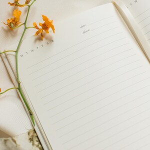 This prayer journal is open with yellow flowers resting on the page. The inside pages are blank and lined.