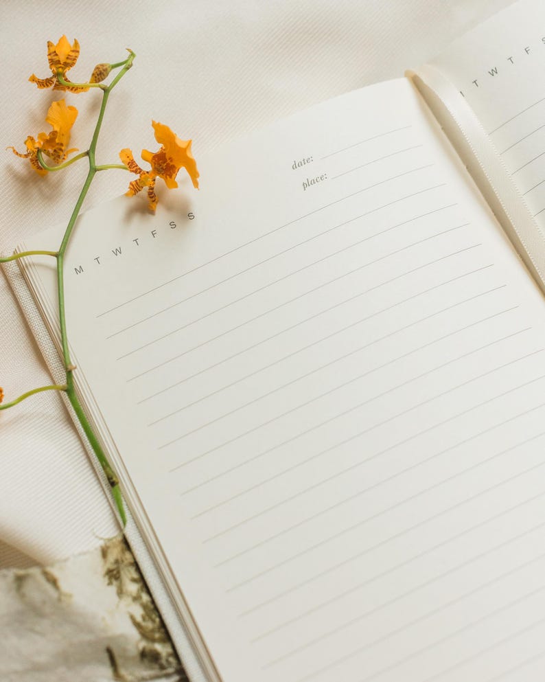 This prayer journal is open with yellow flowers resting on the page. The inside pages are blank and lined.