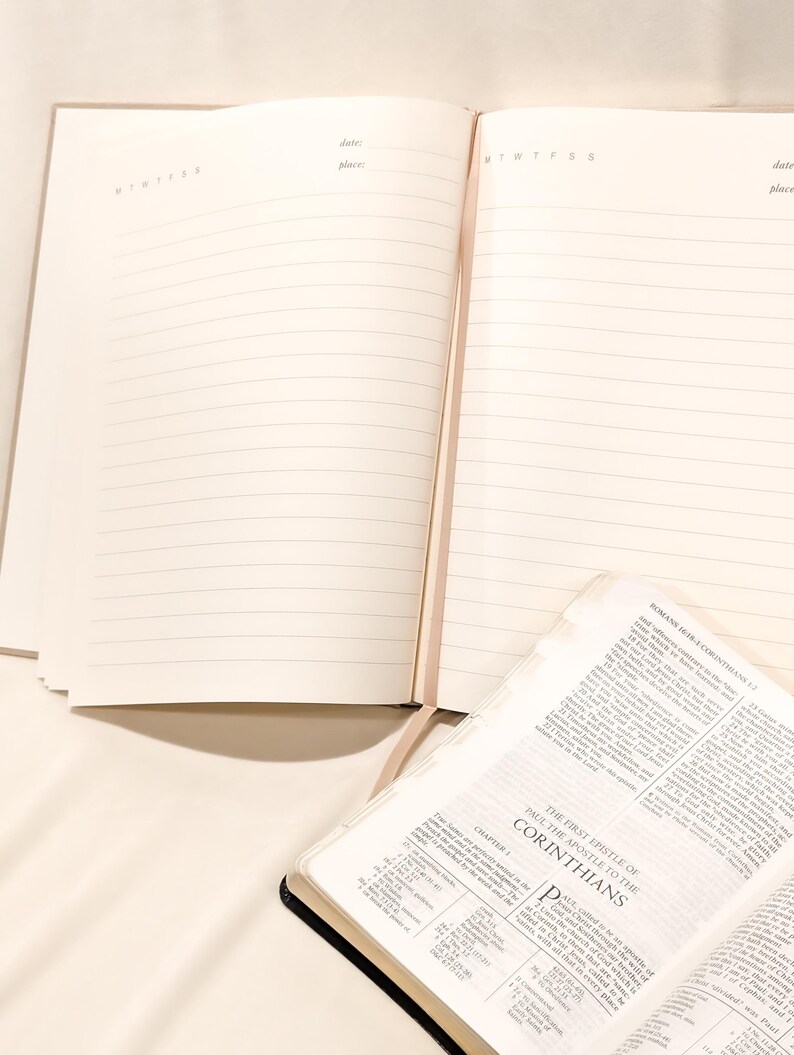 Pu&ograve; includere: Un diario beige aperto con pagine a righe, accanto a una Bibbia aperta. Il diario ha intestazioni per data e luogo. La Bibbia &egrave; aperta al primo capitolo di Corinzi.