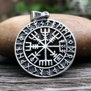 May include: Silver pendant featuring a circular compass with a Vegvisir symbol in the center surrounded by runes. The pendant is a popular symbol of protection and guidance.