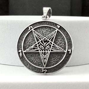 Könnte beinhalten: Silberner Anhänger mit einem Pentagramm, in dem sich ein Ziegenkopf befindet. Das Pentagramm ist von einem Kreis mit hebräischen Buchstaben umgeben.