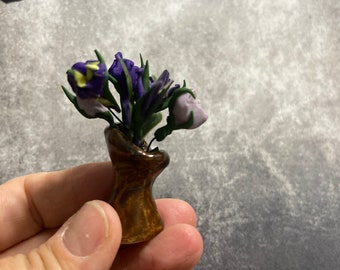 茶色の陶器の花瓶に入った紫色の花。手作りのポリマークレイと窯焼きの陶器。