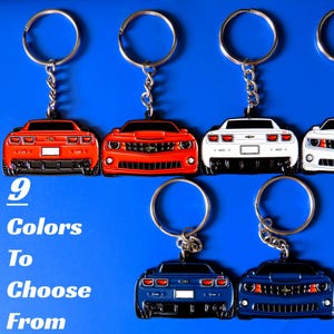 May include: Keychains in various colors shaped like sports cars, each attached to a silver keyring. The image includes red, white, and blue keychains, with the text "9 Colors To Choose From" in white.