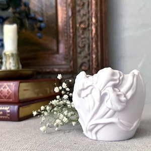 May include: White ceramic planter shaped like an iris flower. The planter is a light shade of white and has a smooth, glossy finish.