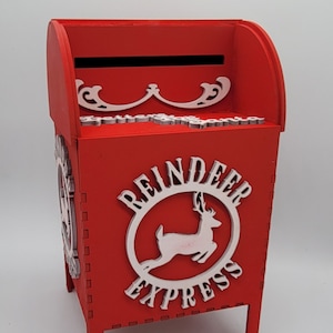 May include: Red wooden mailbox with a white reindeer and "Reindeer Express" text on the front. The mailbox has a slot on the top and stands on four legs.