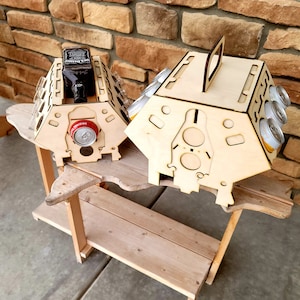 May include: Wooden crate with a handle, designed to hold six cans and a bottle. The crate is made of light brown wood and has a natural finish. The crate is sitting on a wooden table.