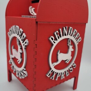 May include: Red wooden reindeer express mailbox with a slot on the top and a white reindeer logo on each side.