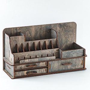 May include: A wooden desk organiser with two drawers and multiple compartments. The organiser is made of dark wood with a light brown stain.