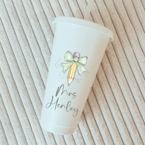 May include: White tumbler with a green bow and a yellow pencil with the text "Mrs. Henley" printed on the side.