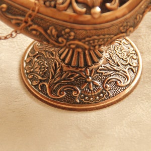 Peut inclure: Une lampe en m&eacute;tal d&eacute;corative avec un design orn&eacute; et une cha&icirc;ne suspendue au sommet. La lampe est en m&eacute;tal de couleur cuivre et a une base d&eacute;taill&eacute;e.