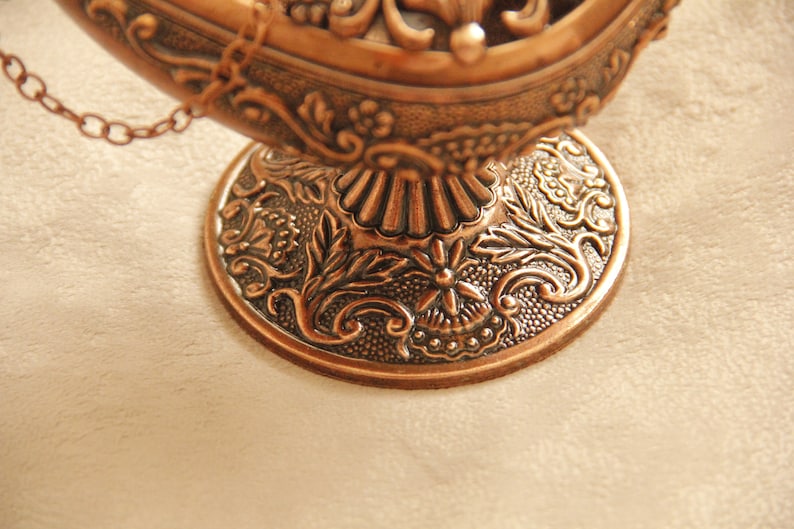 Peut inclure: Une lampe en m&eacute;tal d&eacute;corative avec un design orn&eacute; et une cha&icirc;ne suspendue au sommet. La lampe est en m&eacute;tal de couleur cuivre et a une base d&eacute;taill&eacute;e.