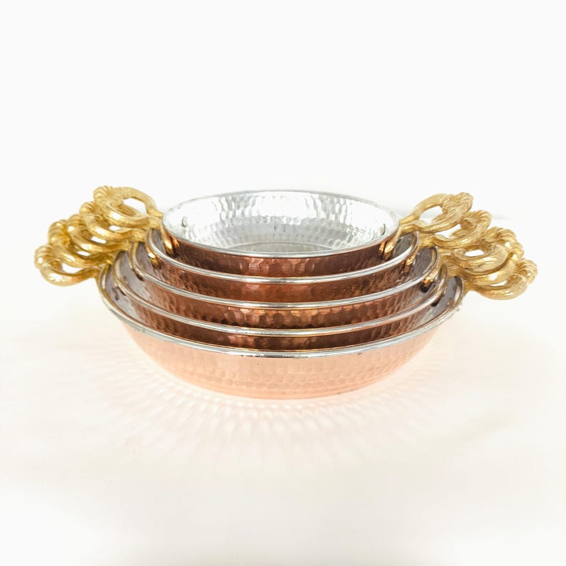 May include: Set of four copper and stainless steel bowls with hammered texture and gold handles.