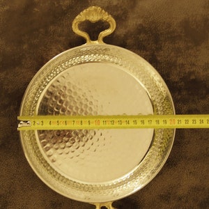 May include: A silver serving tray with two ornate gold handles. The tray is 20 inches in diameter and has a hammered finish.