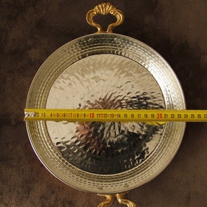 May include: A silver serving tray with hammered texture and two gold handles. The tray is 20 inches in diameter.