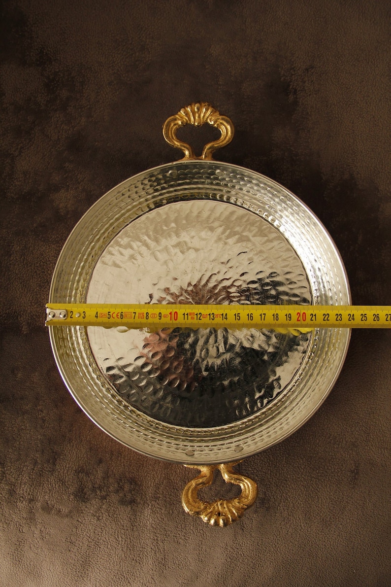 May include: A silver serving tray with hammered texture and two gold handles. The tray is 20 inches in diameter.