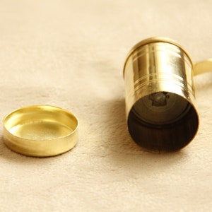 May include: A gold metal grinder with a handle and a removable lid. The grinder is used for grinding spices or other ingredients.