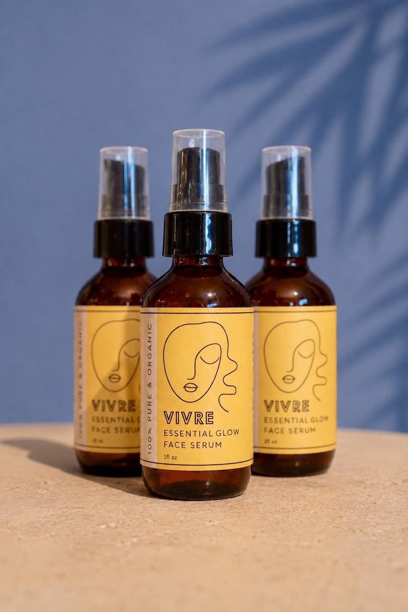 Puede incluir: Tres botellas de vidrio &aacute;mbar de VIVRE Essential Glow Face Serum, cada una con una etiqueta amarilla con un dibujo lineal de una cara. Las botellas tienen tapas de pulverizaci&oacute;n negras y son de 59 ml cada una. El fondo es una pared azul con una sombra.