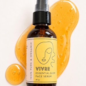 Puede incluir: Botella de vidrio marr&oacute;n de Vivre Essential Glow Face Serum con dispensador de bomba negro. La etiqueta amarilla presenta un dibujo lineal de una cara. Una muestra de suero naranja est&aacute; al lado de la botella. La botella contiene 59 ml.