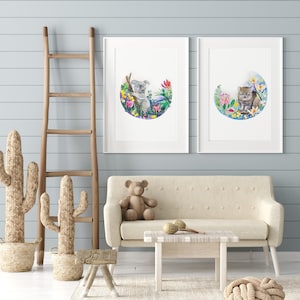 May include: Two framed watercolor illustrations of Australian animals. The left illustration features a koala sitting in a tree with flowers. The right illustration features a wombat sitting in a field of flowers.