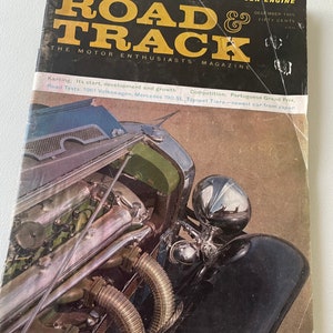 May include: A vintage magazine cover featuring a black and chrome Duesenberg Model J car with the title "Road & Track" and the text "The Motor Enthusiasts Magazine".